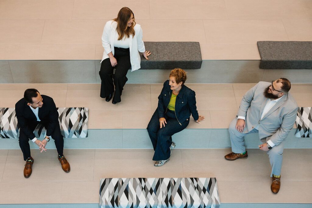 Welsh and Associates Group sitting on stairs and having conversation. 